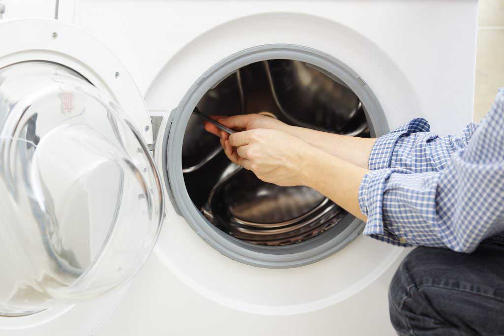 Technician in blue shirt fixes a washing machine